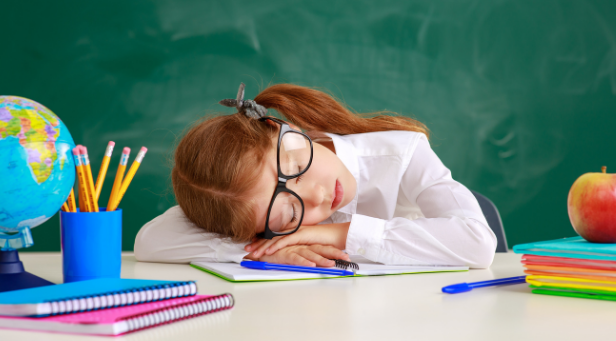 Child dressed as a teacher, sleeping with head on desk.