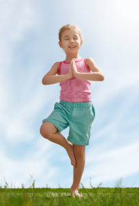 Child standing tall doing a yoga pose.