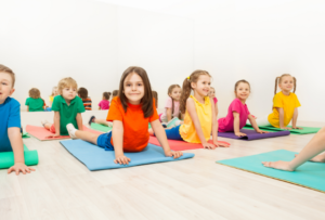Children laying on their stomach on the floor with hands in front pushing themselves up in yoga pose.